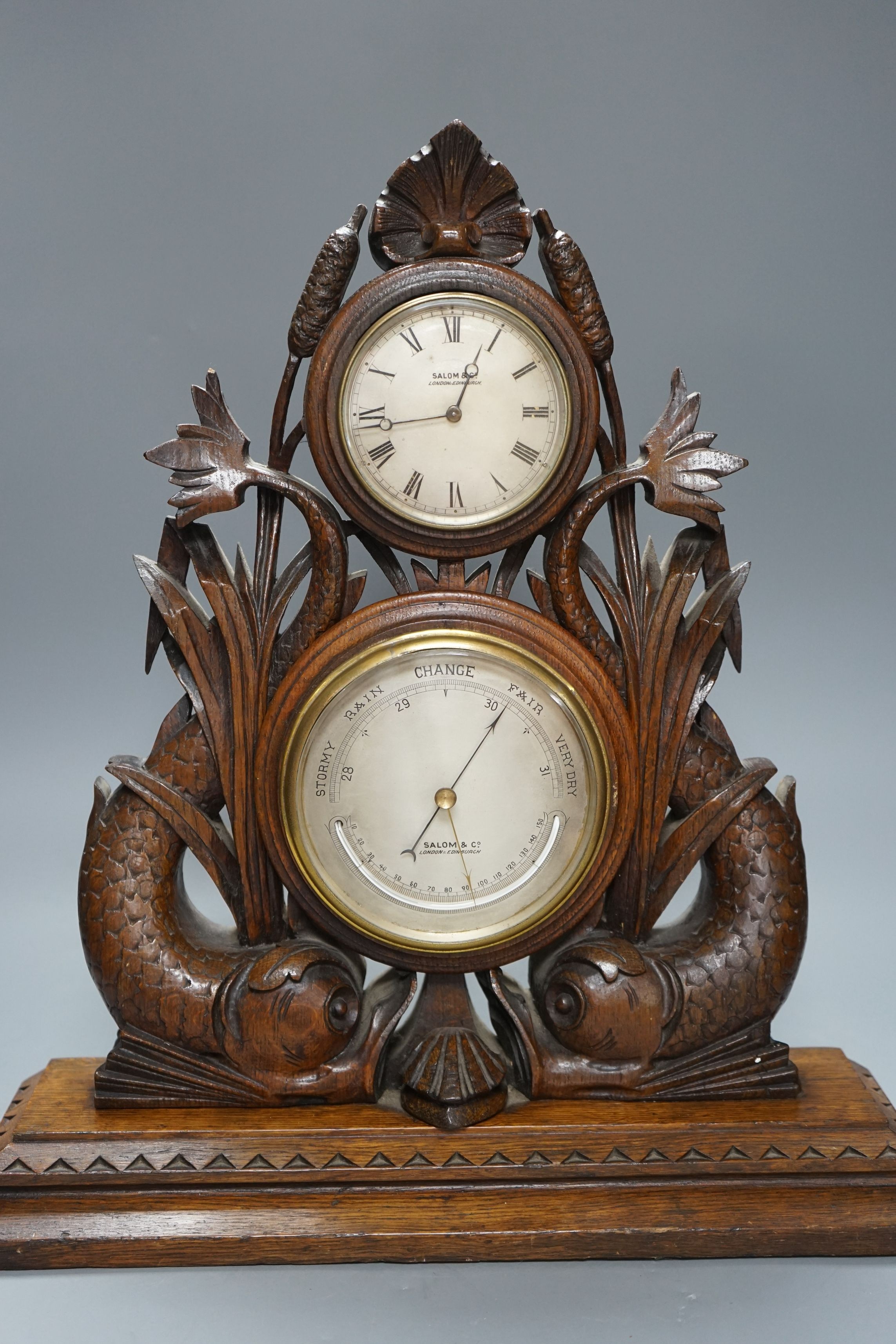 A Victorian oak timepiece combined barometer by Salom & Co., carved with stylised fish and bull rushes, height 46cm